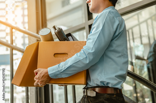 Businessman is carrying a brown cardboard box to resignation