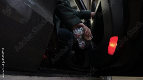 Young woman throws trash through an open car door into the street. Slow motion