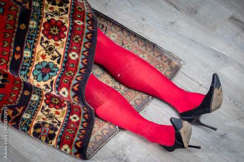 Foto Red female legs in torn tights stick out of the carpet
