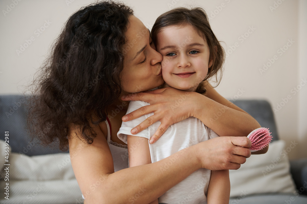 Beautiful baby girl feels happy when her loving mother hugging and kissing her tenderly. Concept of carefree childhood and happy motherhood. Love, tenderness concept Beautiful baby girl feels happy when her loving mother hugging and kissing her tenderly. Concept of carefree childhood and happy motherhood. Love, tenderness concept