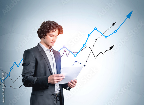 Businessman with paper document standing near rising stock market lines