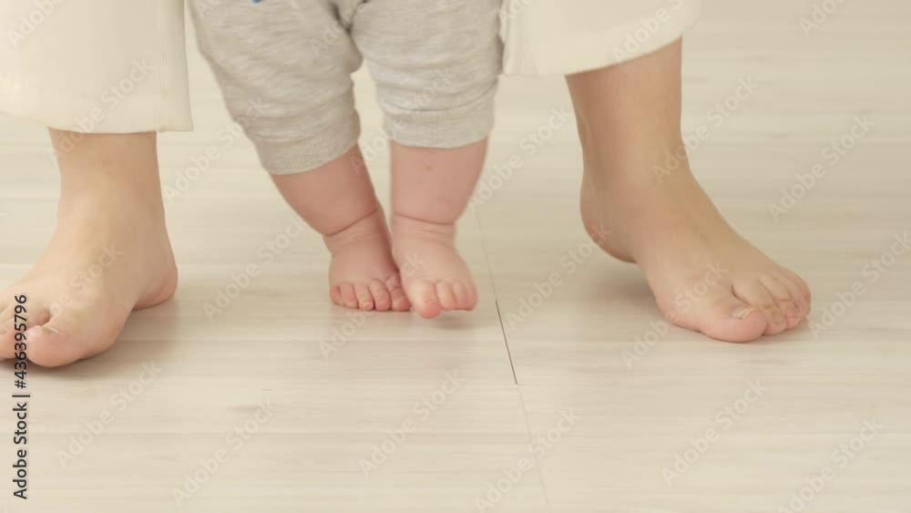 Baby's feet taking steps learning to walk with mothers help. Child 6 months of age. Baby's feet taking steps learning to walk with mothers help. Child 6 months of age.