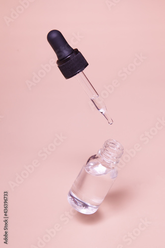 Floating glass dropper bottle with serum or oil and a flying pipette. Skin care minimalist concept mock up