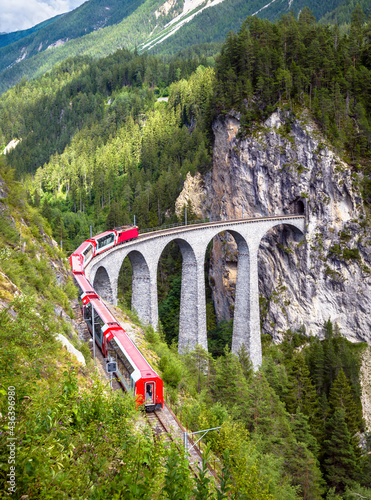 Bernina express train moves on Landwasser Viaduct, Switzerland. Railroad and travel in Swiss Alps concept. photo