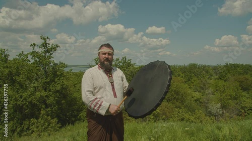 a schuman man plays a shamanic drum, tries to make it rain, worship the old gods and nature. the meaning of the shaman in nature , prores 422, bmpcc4k photo