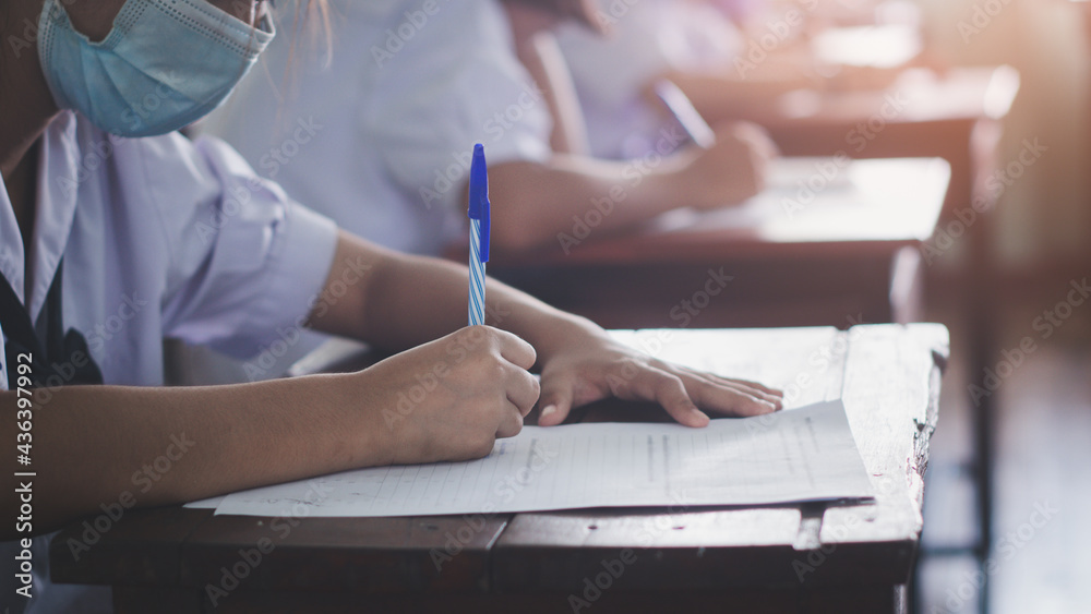 Students wearing mask for protect corona virus or covid-19 and doing exam in classroom with stress Students wearing mask for protect corona virus or covid-19 and doing exam in classroom with stress