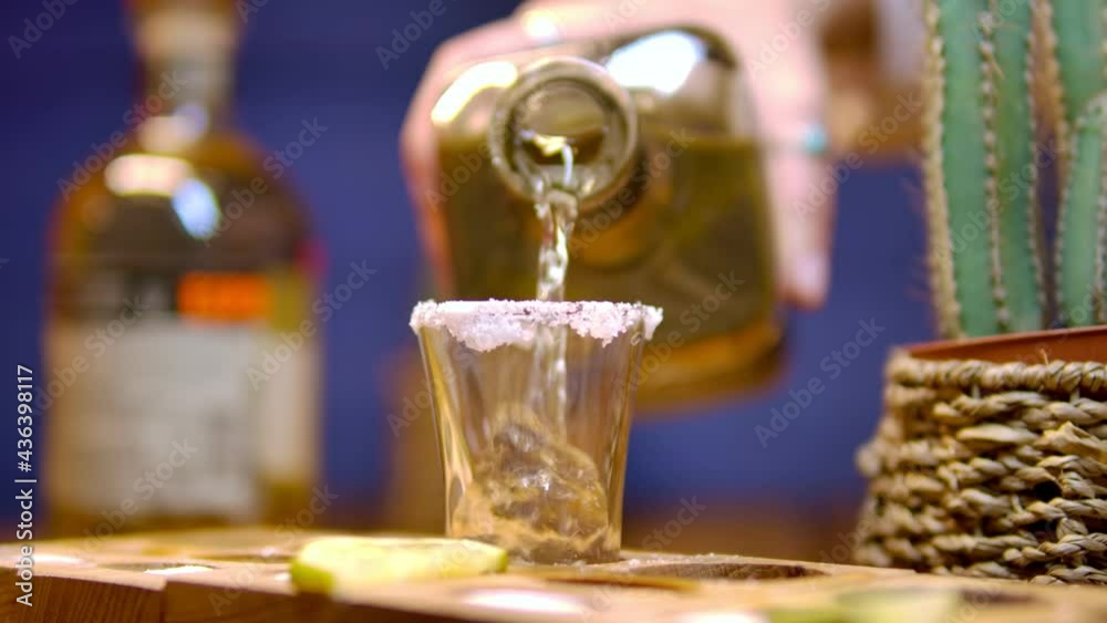 Traditional drink from Mexico tequila.  The bartender's hand pours cold tequila from a bottle into a shot. Party time. Time to drink