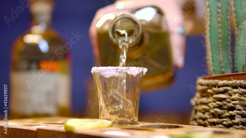 Traditional drink from Mexico tequila.  The bartender's hand pours cold tequila from a bottle into a shot. Party time. Time to drink