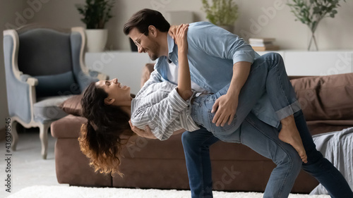 Φωτογραφία Happy young multiracial couple relax dance waltz together in living room on family weekend