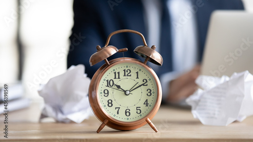 Fotografija Close up of stylish vintage alarm clock among thrown crumpled paper drafts on office desk