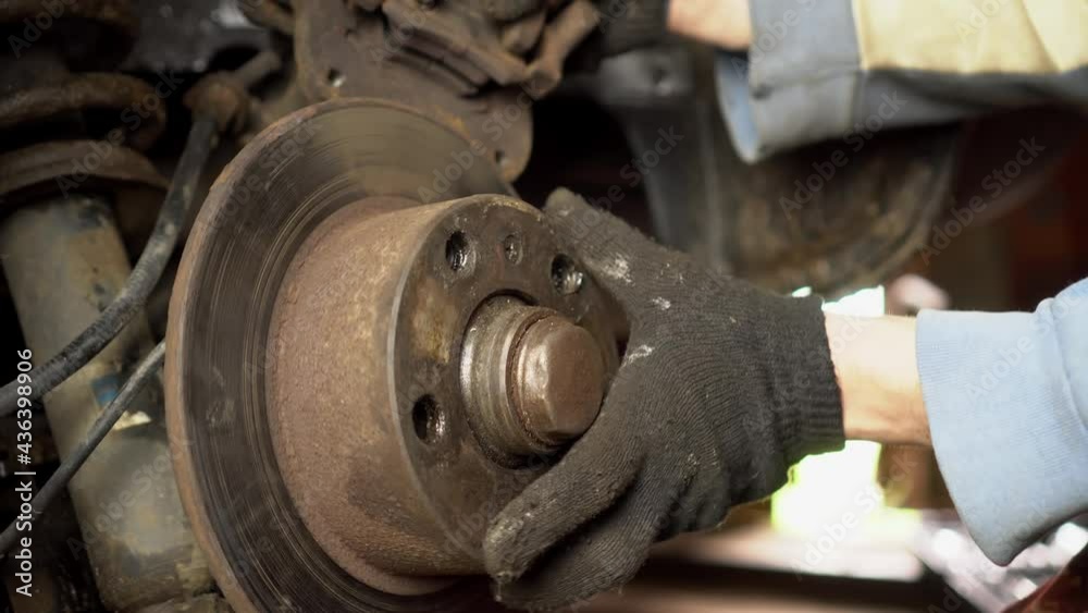 The hands of a master or car mechanic repair the brakes in the car. It removes the brake caliper to replace the brake disc or pads. Inspection of the car suspension. The hands of a master or car mechanic repair the brakes in the car. It removes the brake caliper to replace the brake disc or pads. Inspection of the car suspension.