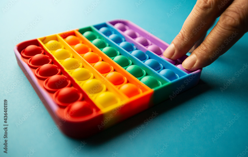 fingers hitting bubbles in a colorful poppit game. Close up photo of poppit, antistress toy fingers hitting bubbles in a colorful poppit game. Close up photo of poppit, antistress toy