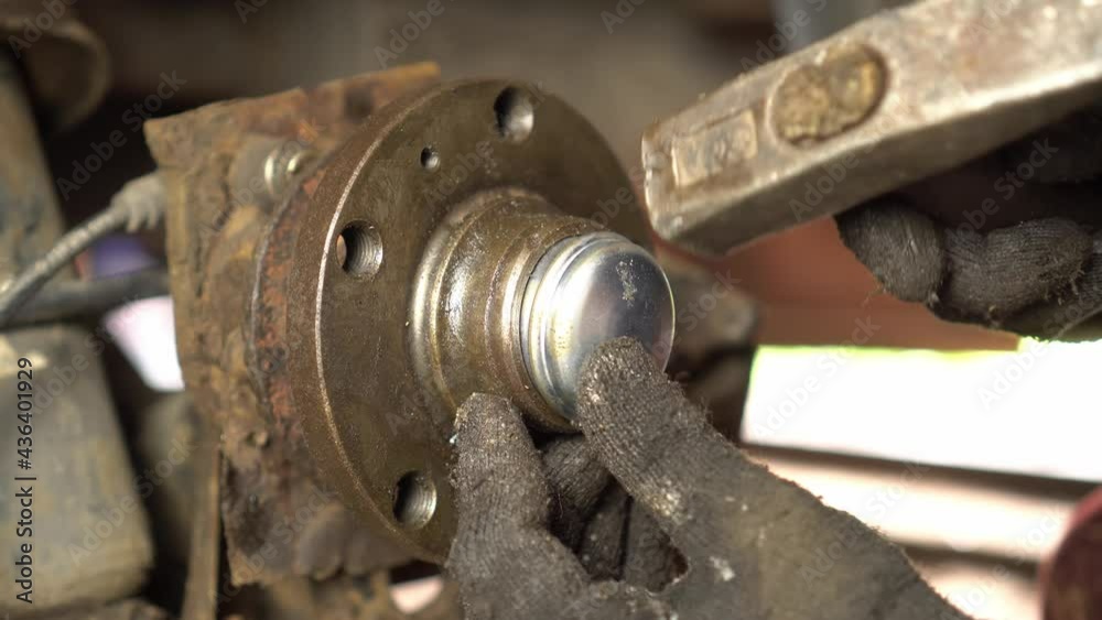 The hands of a master or auto mechanic repair the hub and bearing in the car. He is installing a hub, with a new roller bearing. Inspection of the car suspension. The hands of a master or auto mechanic repair the hub and bearing in the car. He is installing a hub, with a new roller bearing. Inspection of the car suspension.