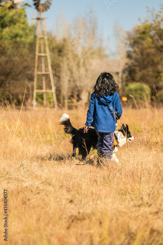 Kid walking a dog on a leash in a field with brown