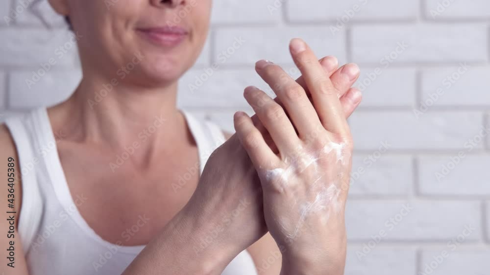 Female use hand cream. A woman apply white soft cream for her hands skin in the room. Female use hand cream. A woman apply white soft cream for her hands skin in the room.