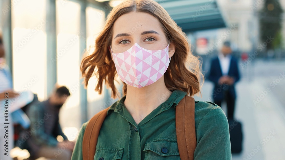 Camera approaching young pretty Caucasian positive woman standing with passport in city looking at camera at bus station. Close up of pretty female in mask travelling, coronavirus, covid pandemic Camera approaching young pretty Caucasian positive woman standing with passport in city looking at camera at bus station. Close up of pretty female in mask travelling, coronavirus, covid pandemic