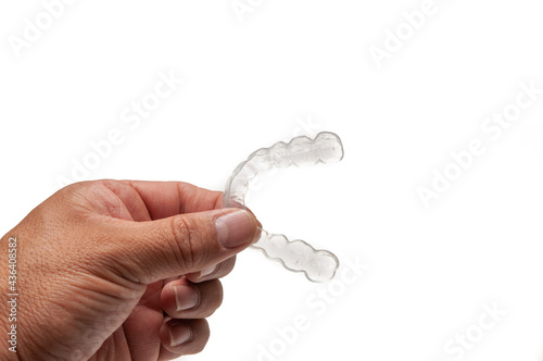 Hand holding dental acrylic retainer. Space for copies