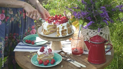 girl putting pieces of homemade strawberry biscuit on a plates. Breakfast on a dinner table in the private summer garden
