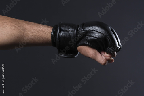 Closeup male fighter hand with MMA glove. Fighter clenched fist before a fight or training in a sports gym.