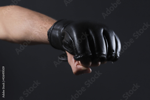 Closeup male fighter hand with MMA glove. Fighter clenched fist before a fight or training in a sports gym.