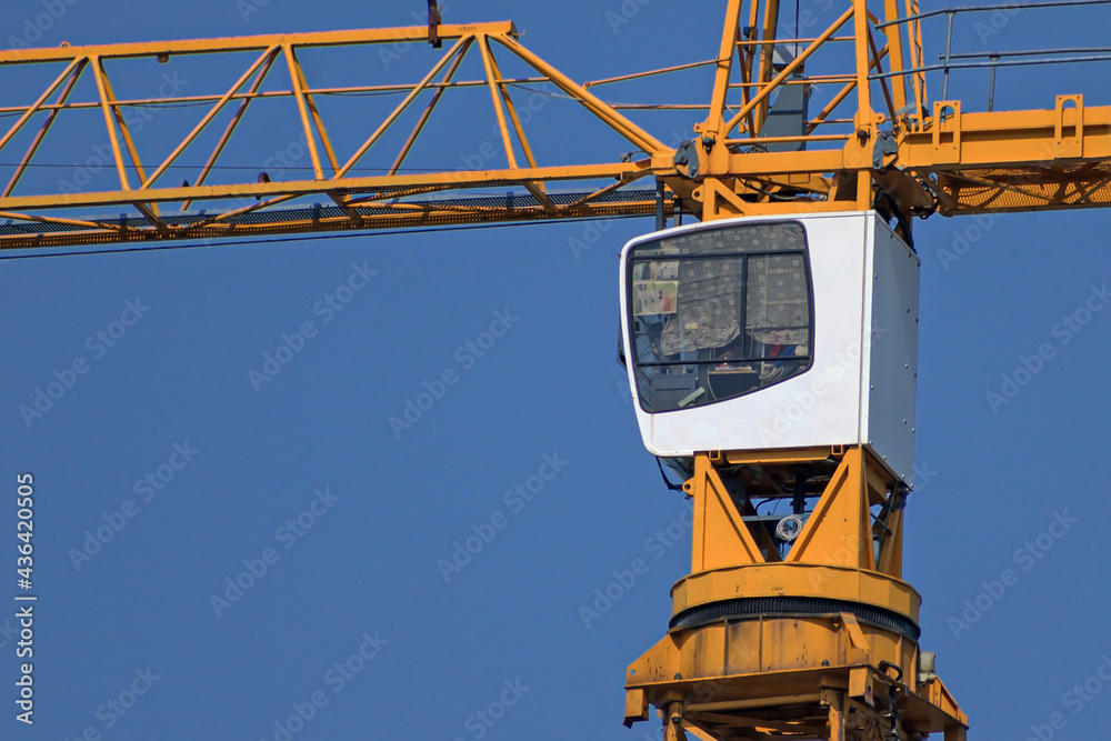 Fototapeta premium Construction crane cab on blue sky background close-up