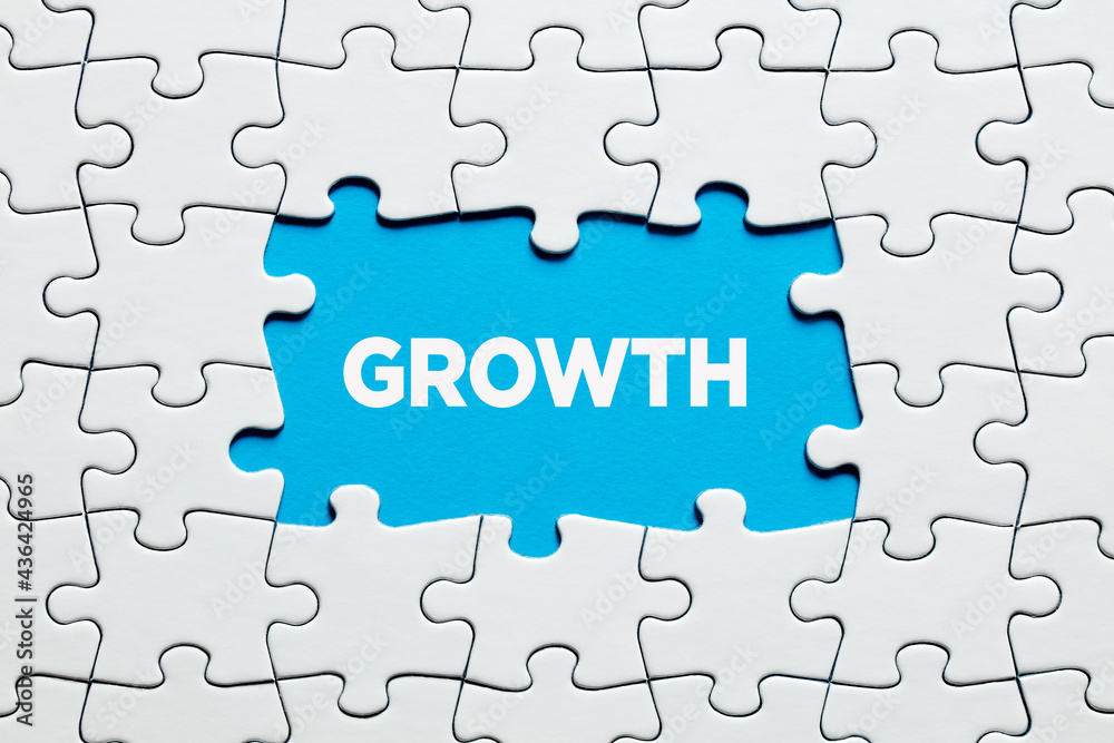 The word growth on blue background surrounded by jigsaw puzzle. Business, financial or personal growth concept. The word growth on blue background surrounded by jigsaw puzzle. Business, financial or personal growth concept.