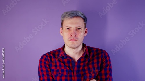Close up of young man getting slapped in face on purple background. Unrecognizable woman hits cheeky guy on cheek deservedly. photo