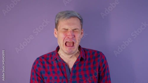 Close up of young man getting slapped in face on purple background. Unrecognizable woman hits cheeky guy on cheek deservedly. photo