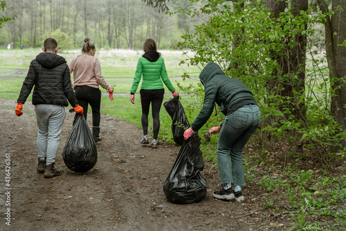 A group of volunteers with garbage bags are cleaning the forest. photo