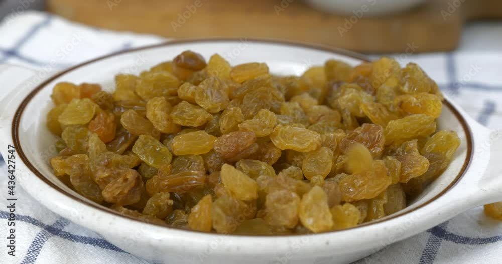 Fresh golden raisins falling into a small bowl Fresh golden raisins falling into a small bowl
