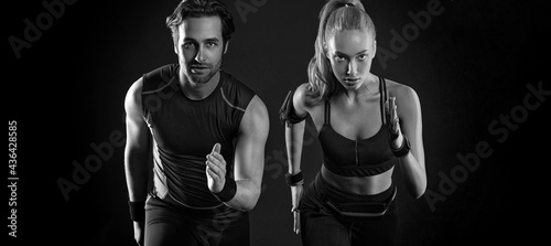 Sprinter run. Strong athletic woman and man running on black background wearing in the sportswear. Fitness and sport motivation. Runner concept. © Mike Orlov