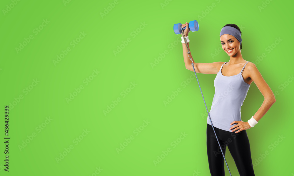 Happy smiling woman doing exercise with growth and dumbbell, isolated over green background. Young sporty model at studio shot. Health, beauty and fitness concept. Happy smiling woman doing exercise with growth and dumbbell, isolated over green background. Young sporty model at studio shot. Health, beauty and fitness concept.