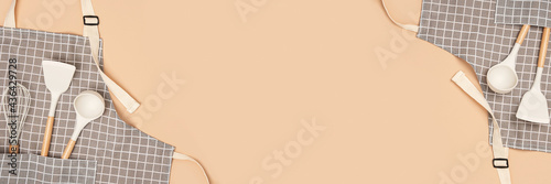 Cooking banner. Flat kitchen accessories. Apron and silicone cooking utensil with wooden handle on beige background with copy space. Top view Flat lay photo