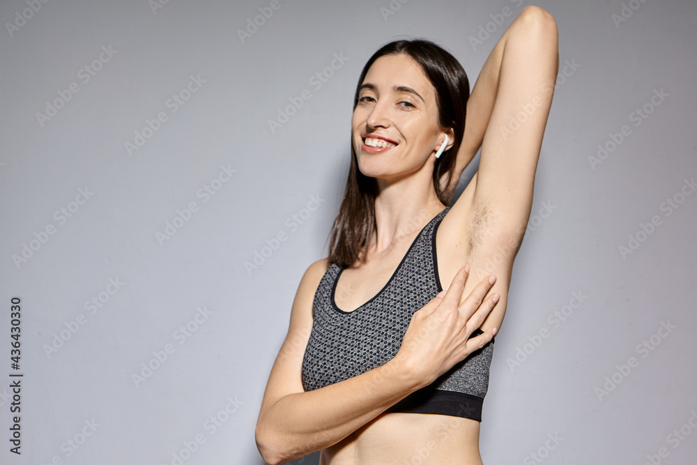 Naklejka premium A woman raised her hand to show the hair under her armpits. A natural girl with unshaven armpits. Feminist concept. A woman with a hairy armpit. Body positive. The feminist movement. Depilation