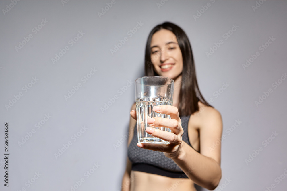 A woman in sports clothes and with wireless headphones drinks water. the concept of a healthy lifestyle and sports activities A woman in sports clothes and with wireless headphones drinks water. the concept of a healthy lifestyle and sports activities