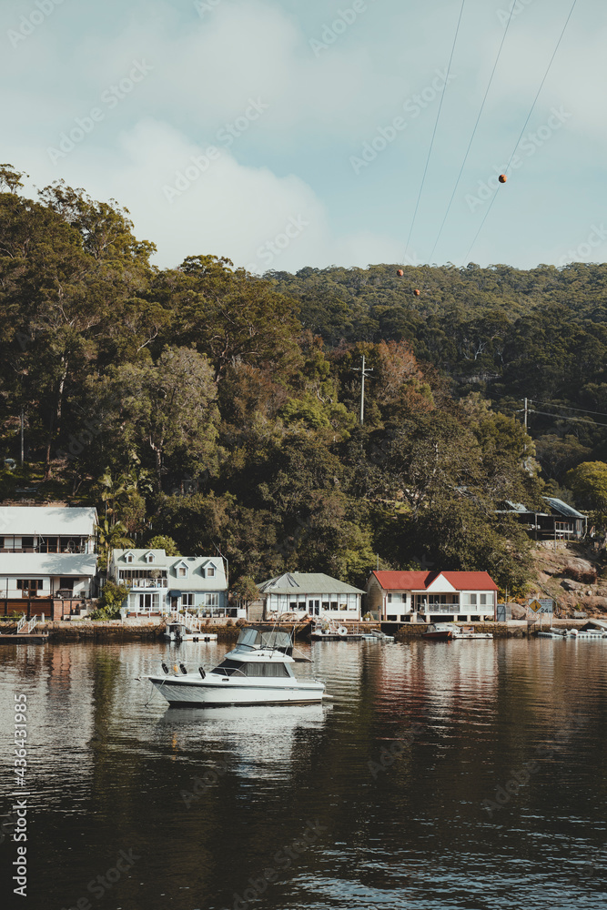 Fototapeta premium Boats on the water in front of idyllic waterfront houses at Berowra Waters NSW. As seen from the Great North Walk.