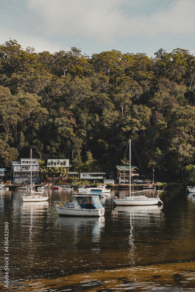 Boats on the water in front of idyllic waterfront houses at Berowra Waters NSW. As seen from the Great North Walk.
