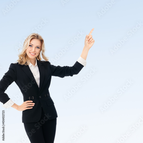 Portrait of happy smiling young cheerful businesswoman, showing something or blank copyspace area for slogan or text message, on blue background. Success in business, job and education concept.
