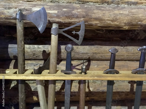 Weapon of the ancient knights sword, axes stand on the background of a wooden wall