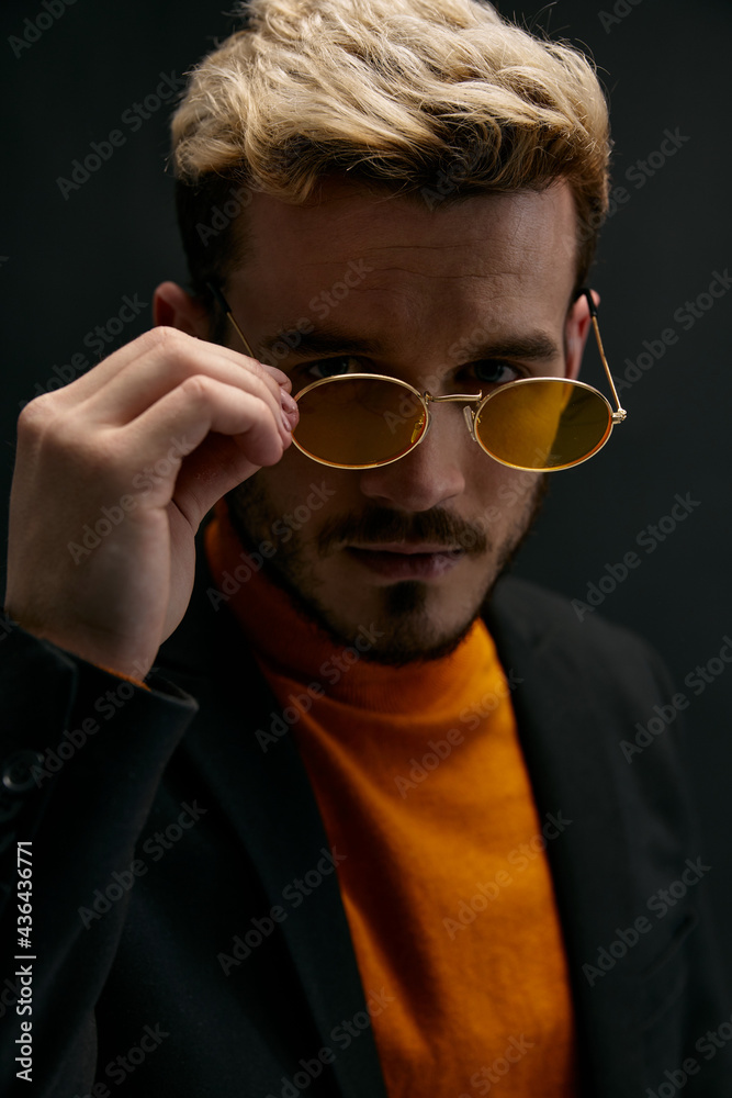 Fototapeta premium man blond in glasses and an orange sweater jacket dark background model close-up