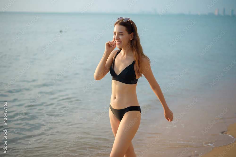 Beautiful woman in black bikini is walking on the beach Beautiful woman in black bikini is walking on the beach