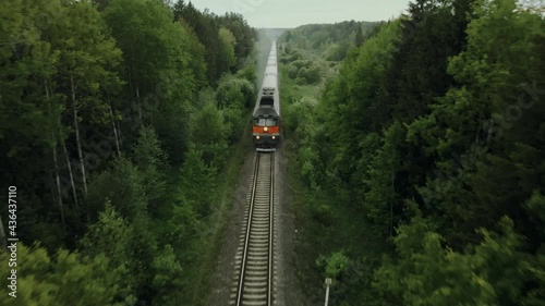Passenger train rides on a railway in a beautiful forest shooting from the air. The drone's camera follows the train from the air. photo