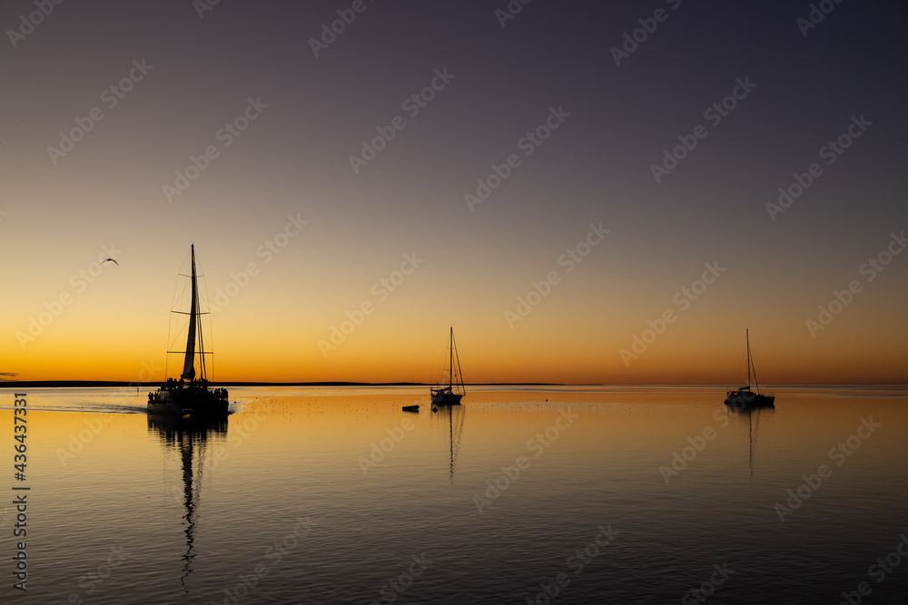 sunset with sail boats in mirror like ocean at Monkey Mia, Western Australia sunset with sail boats in mirror like ocean at Monkey Mia, Western Australia