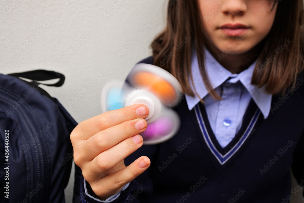 Schoolgirl playing with pop it  fidget spinner toy in school - obrazy, fototapety, plakaty 
