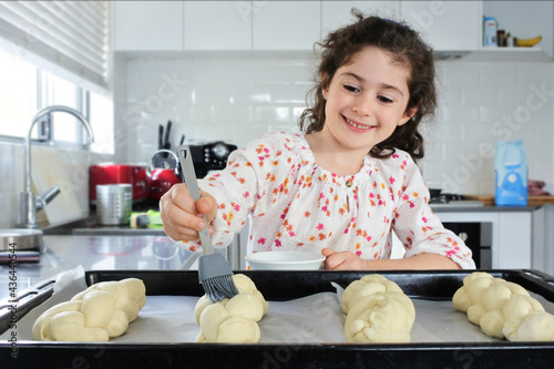 Happy Jewish girl baking sweet Challah bread for Sabbath Jewish Holiday photo