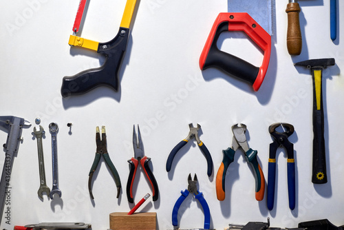 A set of tools hanging on a white wall.