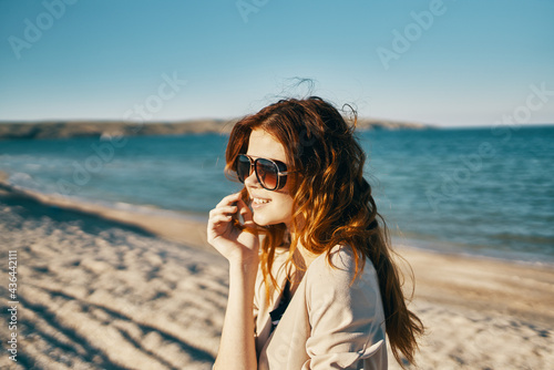 woman in sweater and sunglasses on the beach near the sea in the mountains