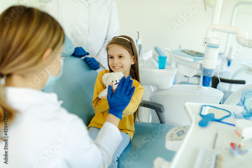 Woman doctor is giving hi five to little girl after a successful dental examination.
