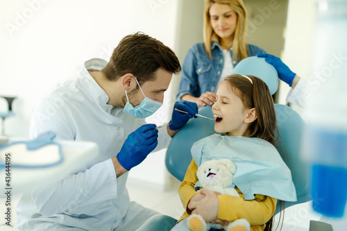 Young girl having check up at dentists surgery with mother.