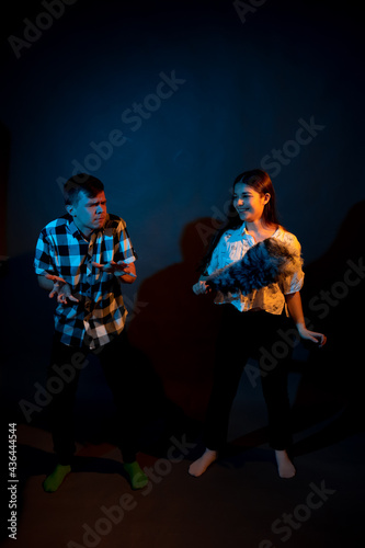 A guy in a plaid shirt and a girl with a dust brush against a dark background